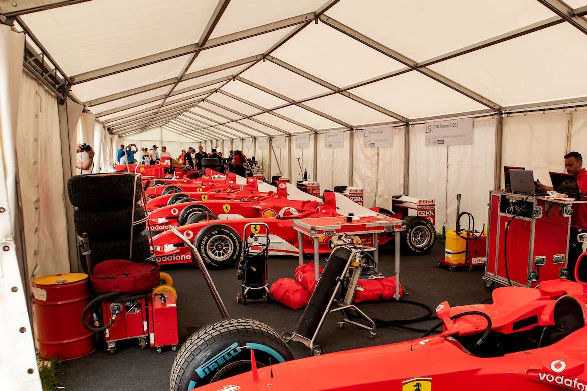 a group of red race cars lined up inside of a tent